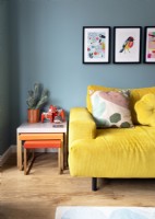 Yellow sofa and orange nest of tables in colourful living room