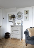 Distressed antique chest of drawers and paintings on wall