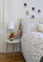 Small round bedside table and display of photographs on bedroom wall