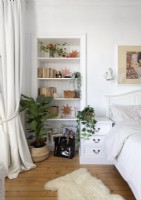 Alcove shelving in white bedroom with wooden flooring