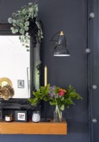 Flower arrangement against black wall on wooden mantelpiece