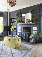Black painted wall around fireplace and gold trunk coffee table