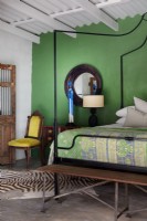 Bedroom with metal four-poster bed and green feature wall