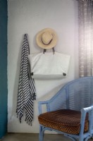 Sarong, bag and sun hat hanging above rattan chair