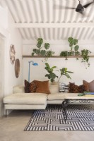 L-shaped sofa, patterned rug and plants on shelf in living room