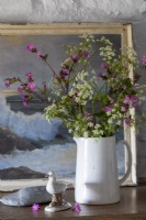 Vase of wildflowers on chest of drawers, old Maritime painting behind and whitewashed walls