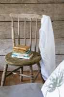 Detail in bedroom of wooden chair, and vintage books