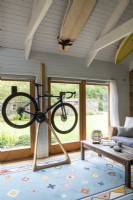 Sally and John Biddle's house in Cornwall, converted barn, Mountain bike hangs from a wooden frame, open beams and tongue and groove decoration
