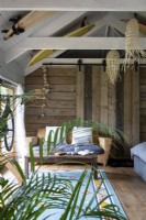 Converted barn with open beams and rustic wooden walls and surf boards as decoration 