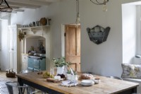 Sally and John Biddle's house in Cornwall, country kitchen, with whitewashed walls and beams. Large kitchen table and Aga cooker.