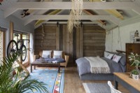 Converted barn, with bed, sofa, and wooden beams with rustic decoration.