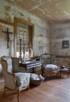 Vintage armchairs in rustic living room with distressed paint on walls