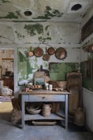 Copper pots and pans in rustic kitchen with distressed furniture and walls