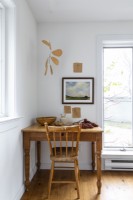 Simple wooden desk and chair with framed painting on white wall