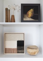 Framed paintings and ornaments on white shelf unit