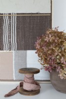 Off-cuts of linen fabric on wooden reel next to flower arrangement