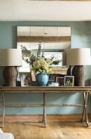 Large wicker lamps and mirror over wooden sideboard table