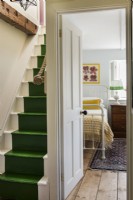 View into vintage style bedroom from landing with green painted stairs