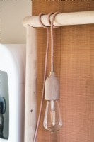 Bare bulb light fitting hanging over wooden bed frame