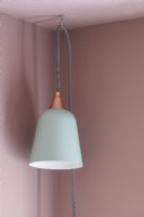Detail of white lamp hanging against pink wall and ceiling 