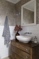 Sink on wooden chest of drawers in simple country bathroom