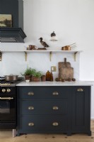 Dark grey kitchen unit with white worktop and cooking accessories