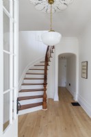 White and wooden curving staircase in minimal country hallway