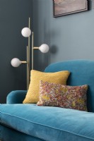 Detail of colourful cushions on blue velvet sofa