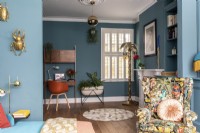 Colourful sitting room with blue painted walls and shutters