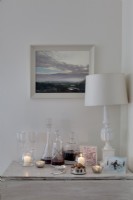 white side table dressed with carafes of wine and white table lamp