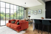 Contemporary open plan dining living area with orange sofa and crittall windows.