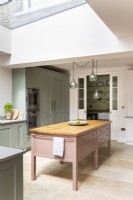 Classic kitchen with large freestanding pink island and a pantry.