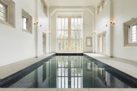 Large indoor swimming pool in a traditional building with floor to ceiling window.