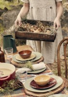 Woman holding a wooden tray of foraged mushrooms outside 
